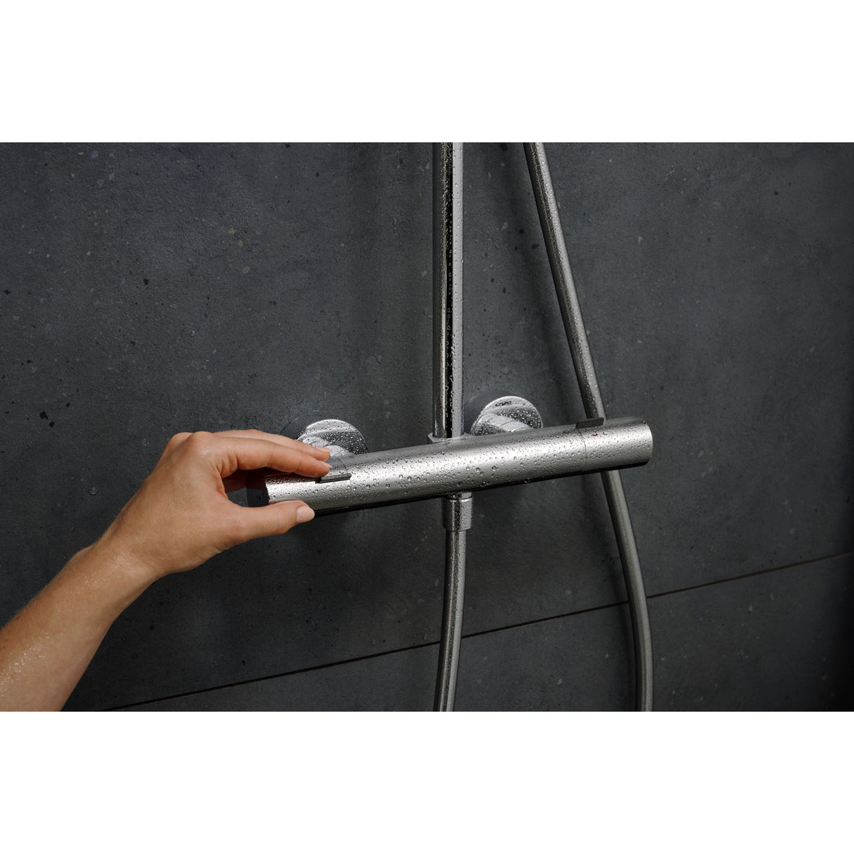 Mitigeur de douche thermostatique Grohe, chrome, sur mur sombre, main réglant le robinet