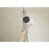 Douchette Grohe noire sur barre de douche chromée, main ajustant la hauteur.