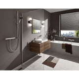 Salle de bain moderne avec robinetterie Grohe, douchette en inox argent, murs gris.