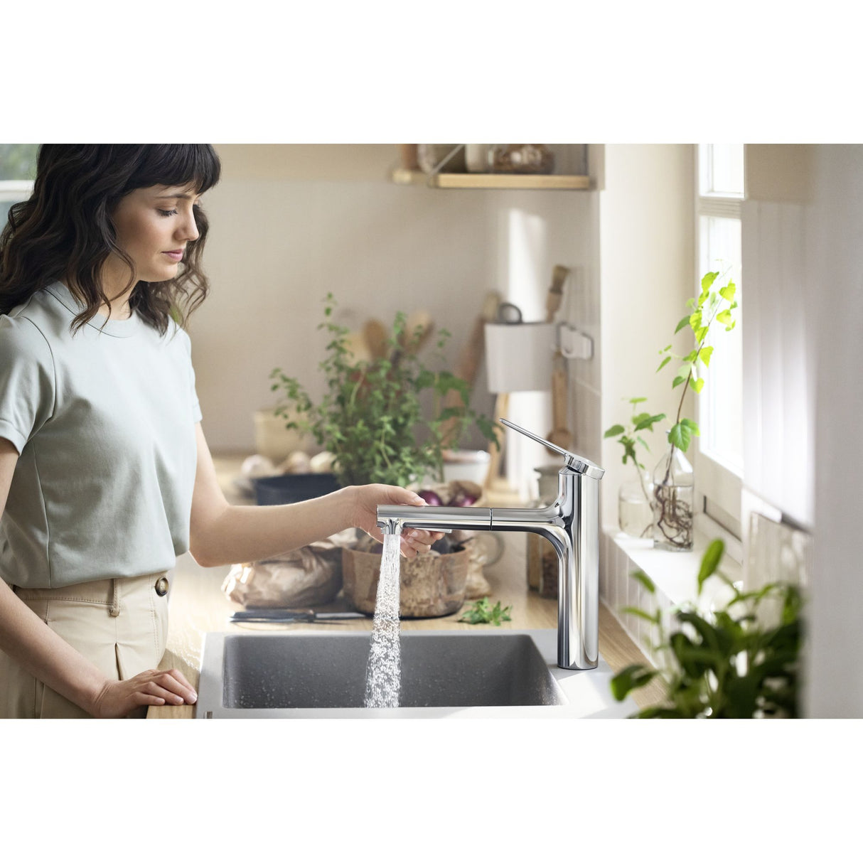 Mitigeur de cuisine Grohe chromé, robinet moderne, femme utilisant le robinet.