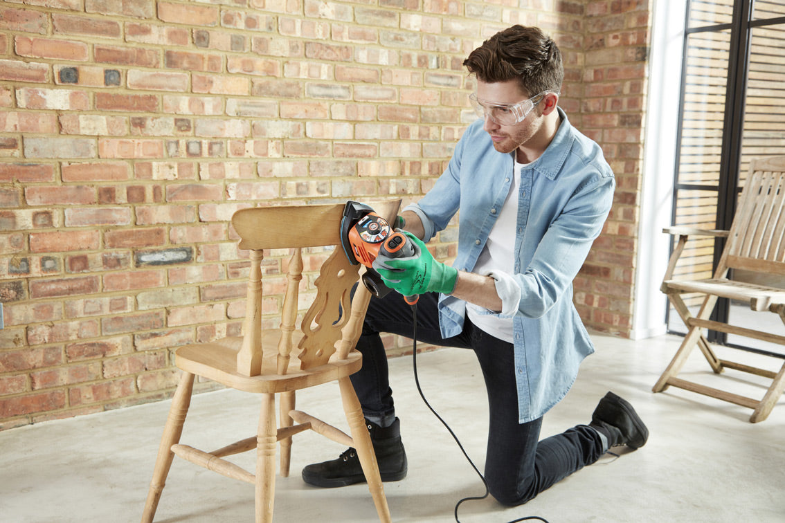 Ponceuse électrique Black+Decker orange, outil de bricolage pour bois, utilisée sur une chaise