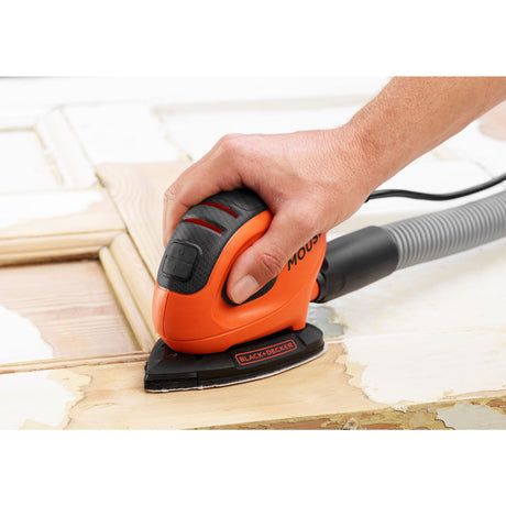 Ponceuse Black+Decker, ponceuse électrique, couleur orange et noire, en action sur du bois.
