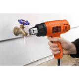 Décapeur thermique Black+Decker, outil électrique orange utilisé sur un robinet gelé.