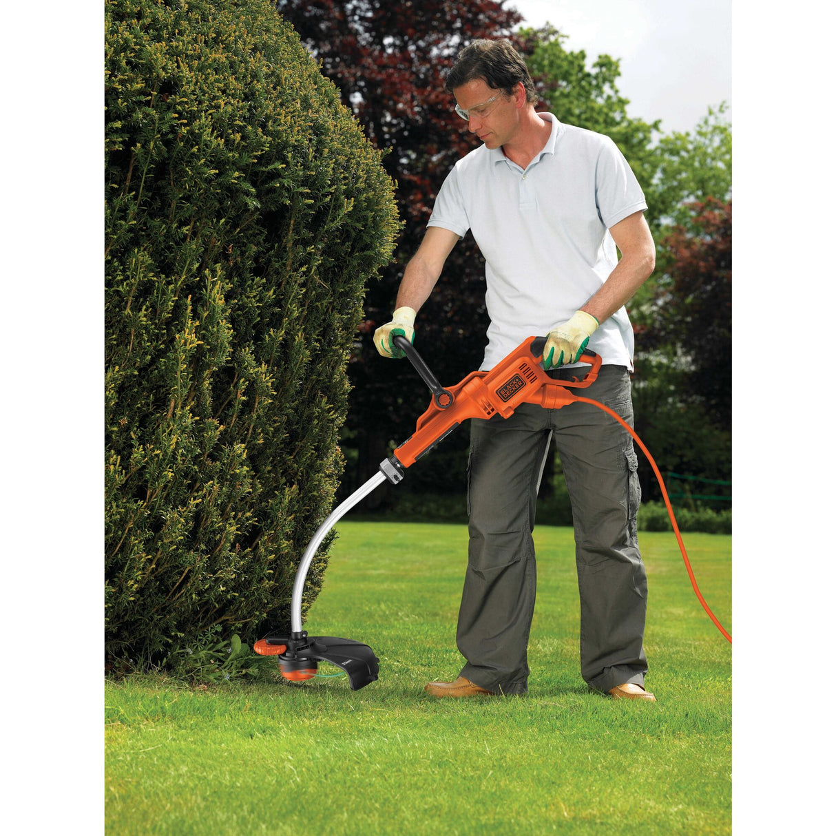 Débroussailleuse Black+Decker, outil de jardinage électrique orange, en action sur pelouse