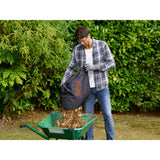 Aspirateur-souffleur-broyeur BLACK+DECKER 2600W avec système bi-tube, noir et orange, prêt à l'emploi dans un jardin.