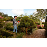 Taille-haie orange Black+Decker utilisé pour la taille de haies dans un jardin.