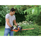 Taille-haie Black+Decker orange en action, outil de jardinage pour haies vertes