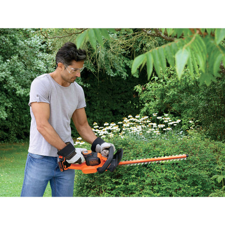 Taille-haie Black+Decker orange en action, outil de jardinage pour haies vertes