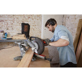 Scie à onglet grise Black+Decker en action sur une planche de bois, atelier bricolage.