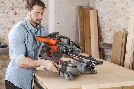 Scie à onglet Black+Decker orange et grise en utilisation sur établi, outil électroportatif professionnel.