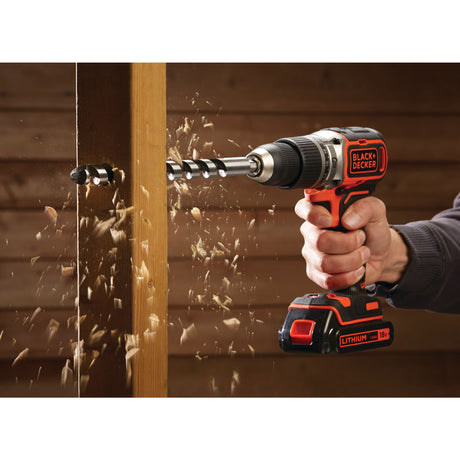 Perceuse sans fil Black+Decker, outil électroportatif noir et orange, en action sur bois.
