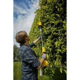 Taille-haie télescopique jaune de marque DeWalt utilisé pour tailler une haie