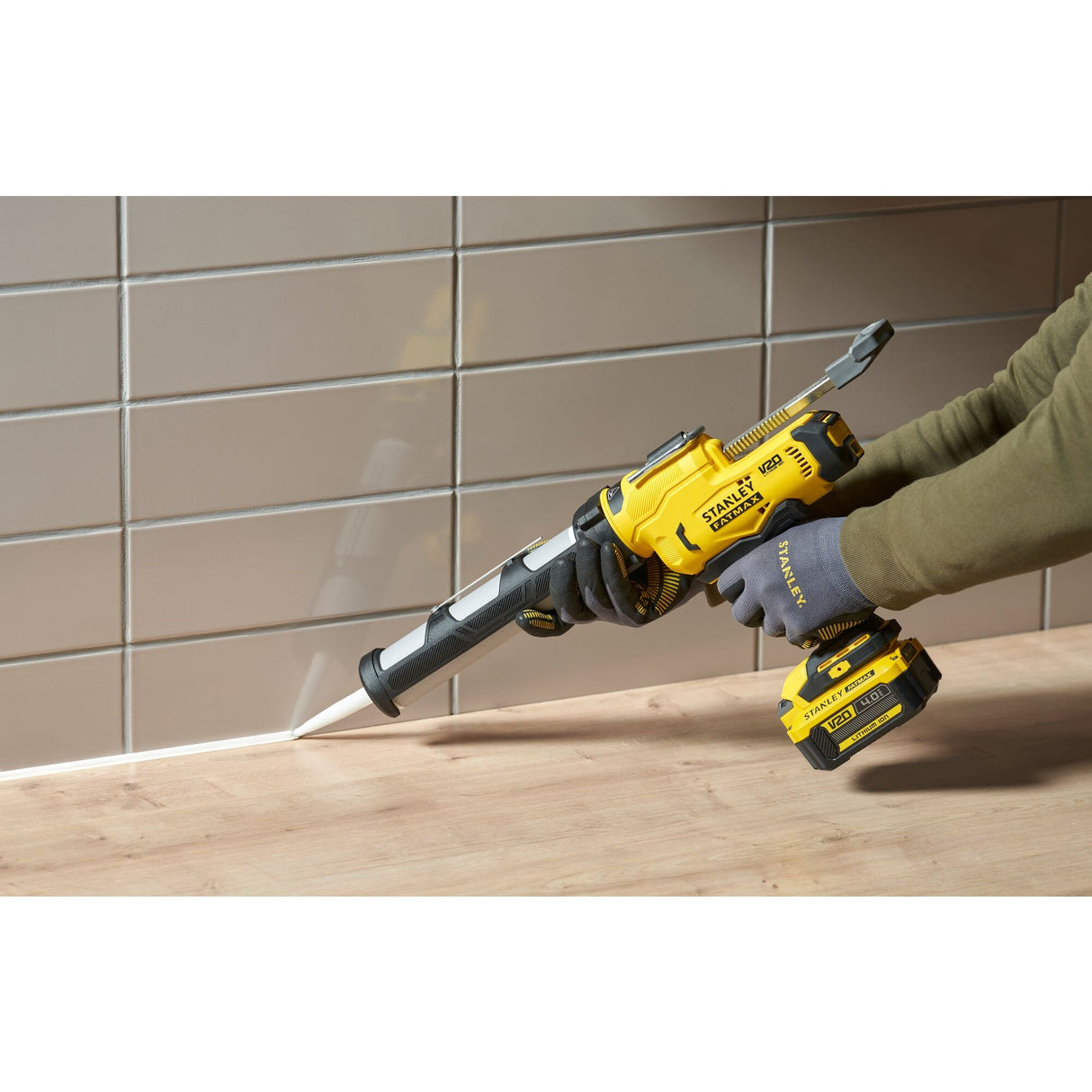 Pistolet à mastic électrique Stanley, outillage jaune et noir, utilisé sur un plan de travail