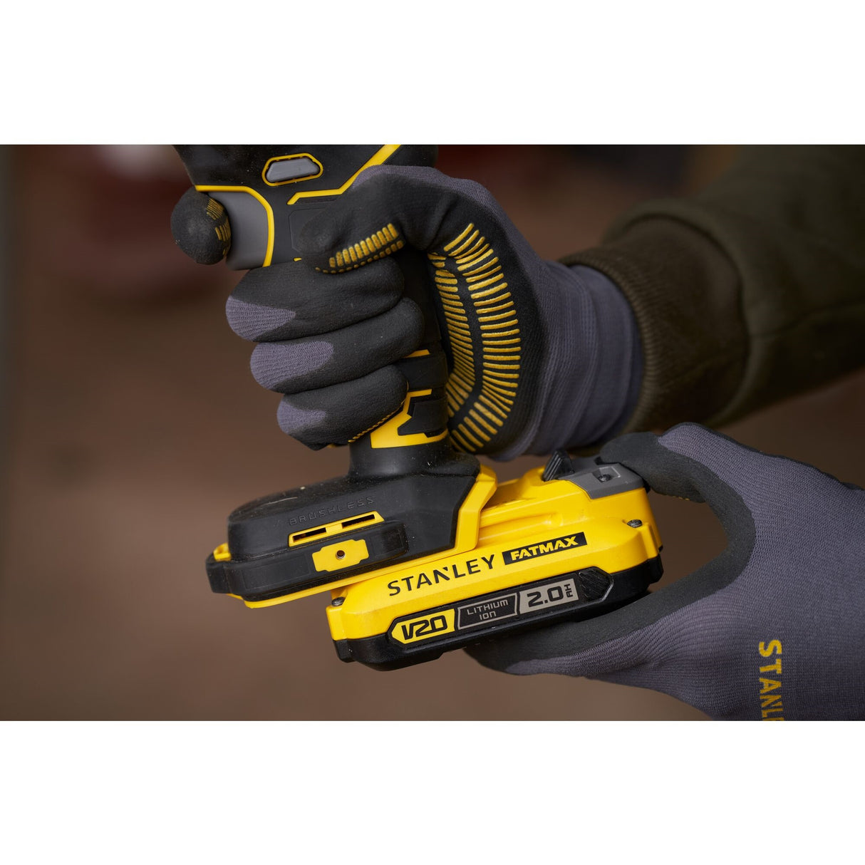 Perceuse visseuse Stanley Fatmax jaune et noire, modèle V20, en main avec des gants.