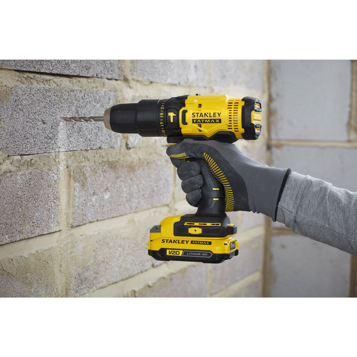 Perceuse sans fil Stanley, couleur jaune et noire, utilisée sur un mur de briques