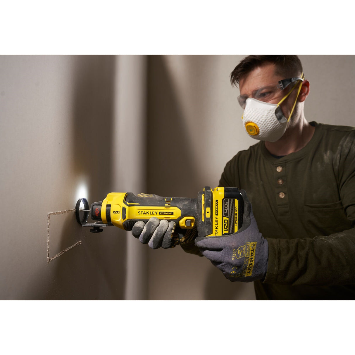 Outil multifonction Stanley, type sans-fil, couleur jaune et noir, en action sur placo.