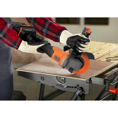 Meuleuse sans fil Black+Decker orange et noire, outil électroportatif en action sur carrelage