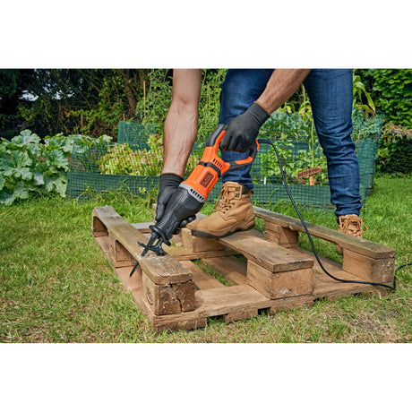 Scie sabre Black+Decker orange, outil électrique utilisé pour couper une palette en bois.
