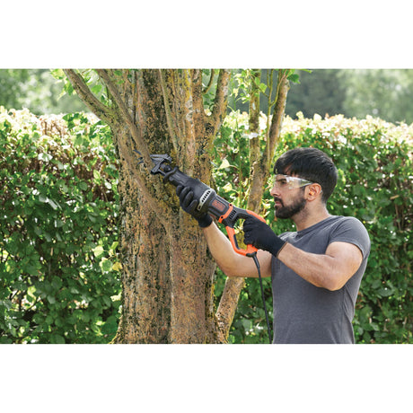 Scie sabre BLACK+DECKER noire et orange pour élagage, utilisée pour couper une branche d'arbre