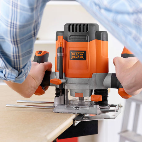 Défonceuse BLACK+DECKER, outil électroportatif orange et noir, en cours d'utilisation sur bois.