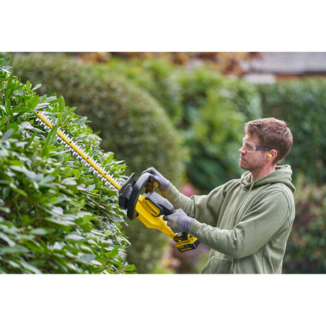 Taille-haie DeWalt jaune, outil de jardinage électrique utilisé pour tailler des haies vertes