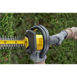 Taille-haie Ryobi électrique jaune et noir en action, utilisé pour tailler une haie verte.