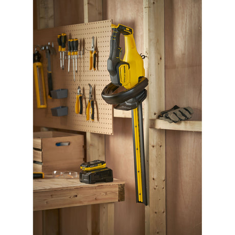 Taille-haie électrique Stanley, jaune et noir, accroché dans un atelier d'outillage.