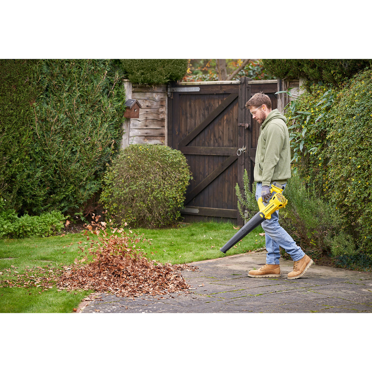 Homme utilisant un souffleur de feuilles jaune Stanley, outil de jardinage, couleur noire et jaune