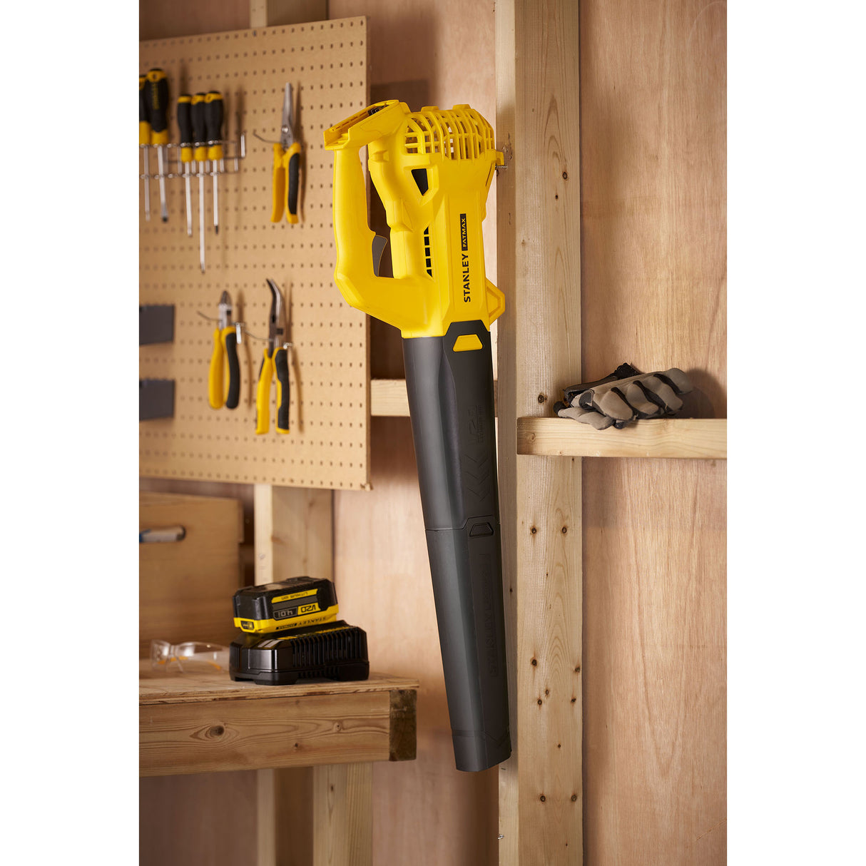 Souffleur sans fil Stanley jaune et noir, outil de jardinage accroché au mur.