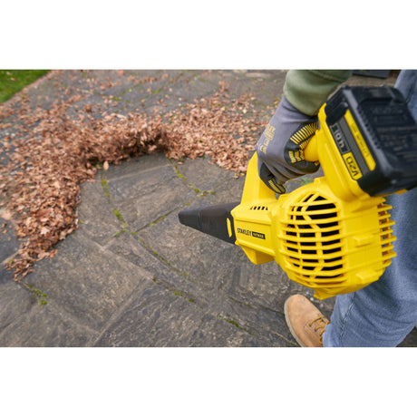 Souffleur à feuilles jaune Stanley Fatmax utilisé sur une terrasse, outil de jardinage électrique