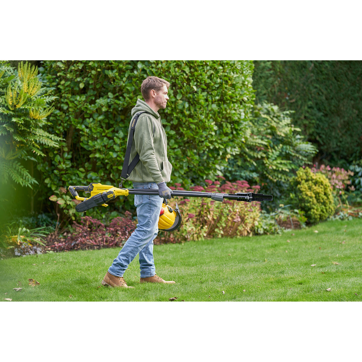 Homme portant une tronçonneuse sur perche jaune Stanley, outil de jardinage, couleur jaune