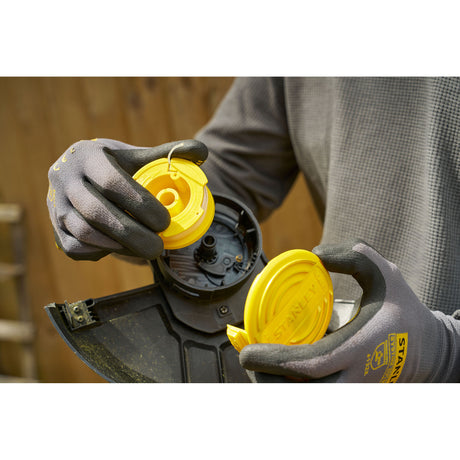 Bobine de fil pour débroussailleuse Stanley, accessoire jaune, manipulation par un utilisateur.