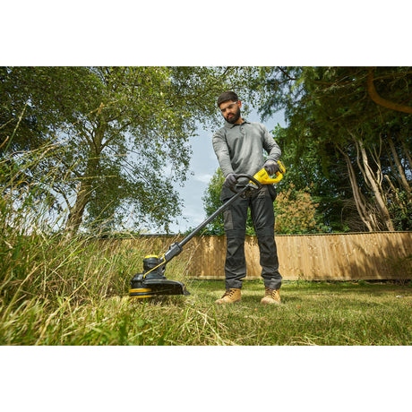 Débroussailleuse DEWALT jaune et noire utilisée par un homme dans un jardin, outil électrique.