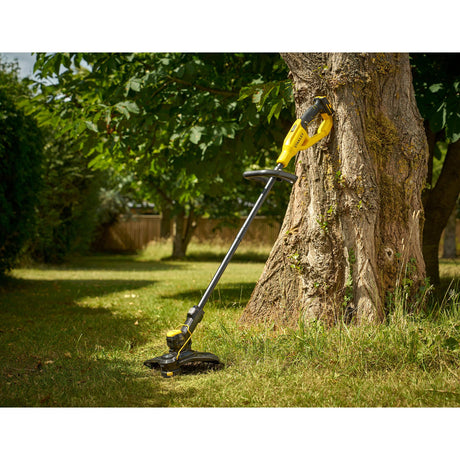 Coupe-bordure DEWALT jaune et noir, outil de jardin électrique posé contre un arbre