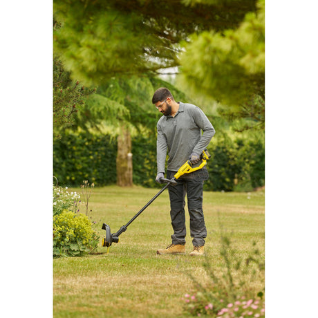 Coupe-bordure jaune Dewalt utilisé en extérieur, outil de jardinage électroportatif.