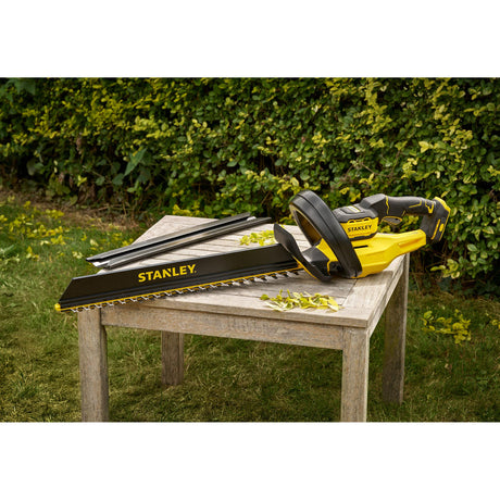 Taille-haie Stanley électrique jaune et noir posé sur une table en bois, outil de jardinage