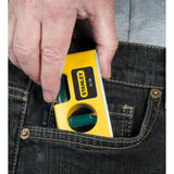 Niveau à bulle Stanley jaune compact, inséré dans une poche de pantalon.