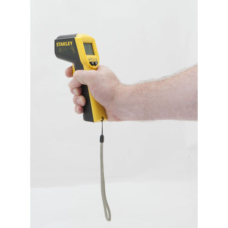 Thermomètre infrarouge Stanley, type pistolet, couleur jaune et noir, tenu en main.