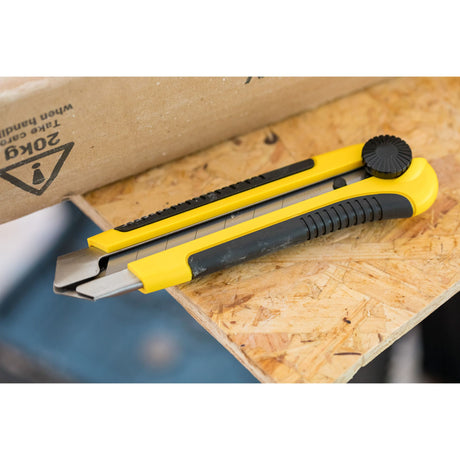 Cutter Stanley, outil de découpe, jaune et noir, posé sur une planche en bois.