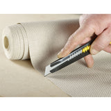 Cutter Stanley, couteau universel noir et jaune, utilisé pour découper un tapis beige.