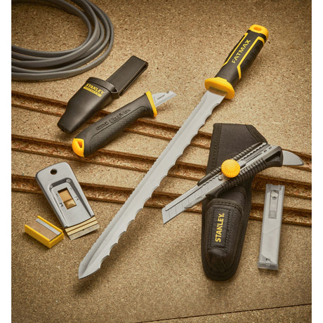 Outils Stanley FatMax, couteau et scie à main, couleur noire et jaune, sur fond de chantier.