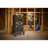 Servante à roulettes noire Stanley, caisse à outils empilable, poignées jaunes, sur chantier