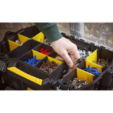 Boîte à outils Stanley noire et jaune, rangement compartimenté avec accessoires, main en action