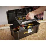 Boîte à outils Stanley noire, type mallette, sur établi avec outils jaunes visibles