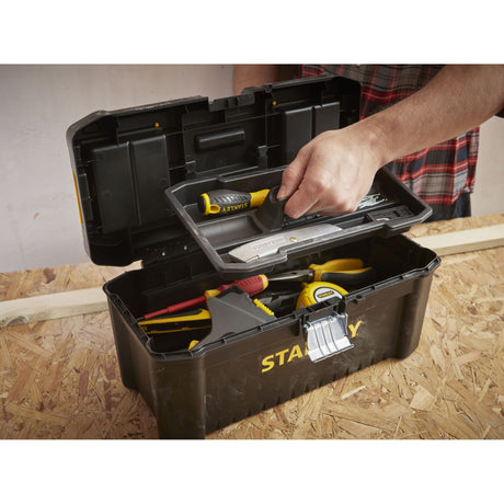 Boîte à outils Stanley noire, type mallette, sur établi avec outils jaunes visibles