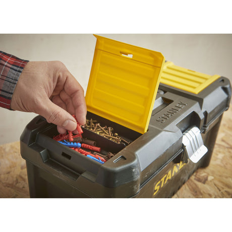 Boîte à outils Stanley noire et jaune, main prenant des chevilles, outillage pratique