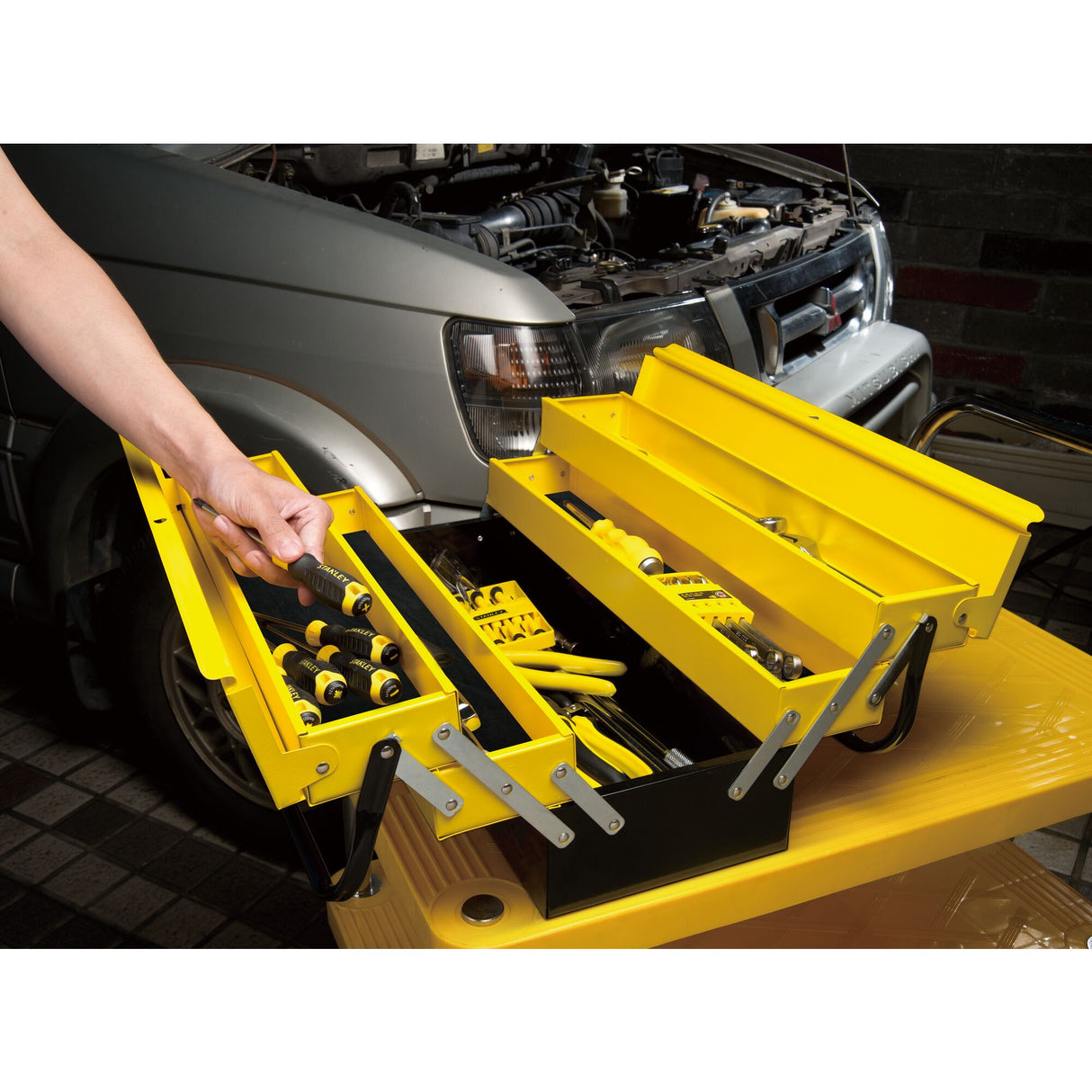 Boîte à outils Stanley jaune et noire, outillage main, utilisée près d’une voiture