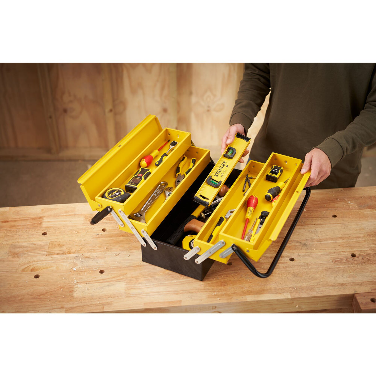 Boîte à outils Stanley jaune et noire, métal, remplie d'outils à main, sur établi