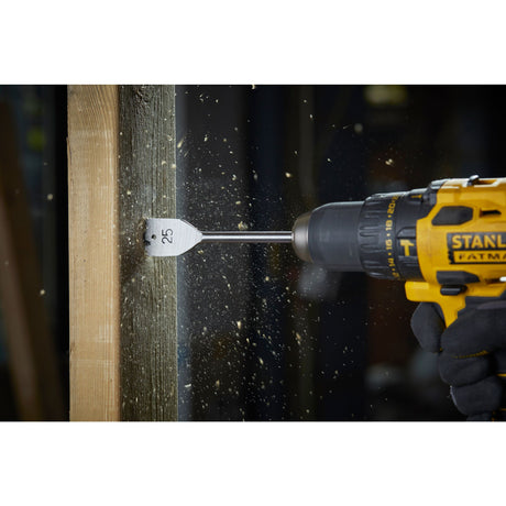 Perceuse Stanley jaune, foret plat gris, outil électroportatif en action sur bois