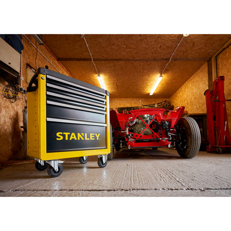 Servante d'atelier Stanley jaune et noire à roulettes, dans un garage.